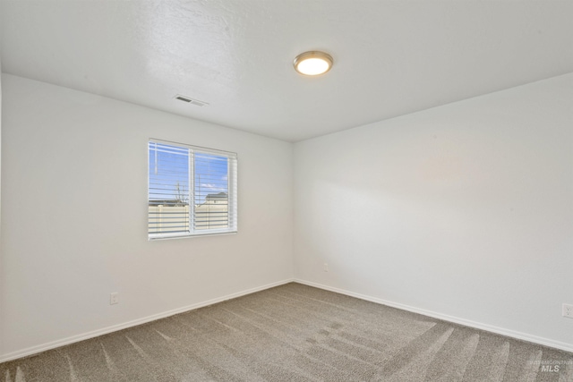 carpeted spare room featuring visible vents and baseboards