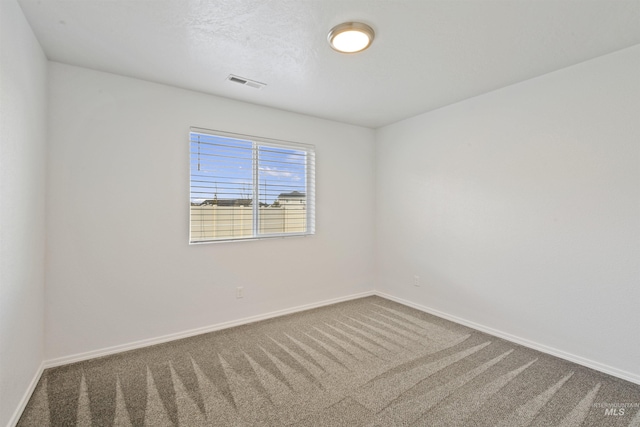 spare room with carpet floors, visible vents, and baseboards