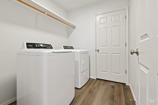 washroom featuring laundry area, baseboards, washer and dryer, and wood finished floors