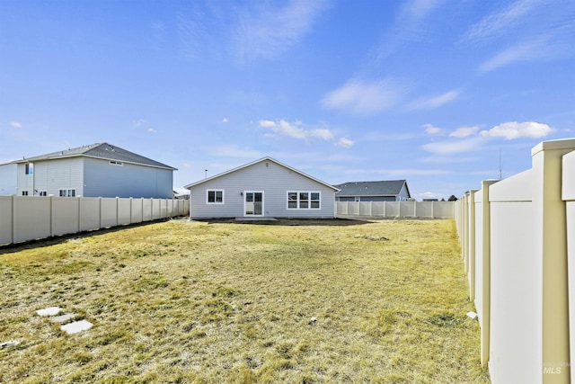 rear view of house featuring a fenced backyard and a lawn