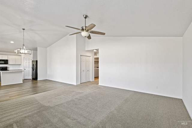 unfurnished living room featuring lofted ceiling, a ceiling fan, and carpet flooring