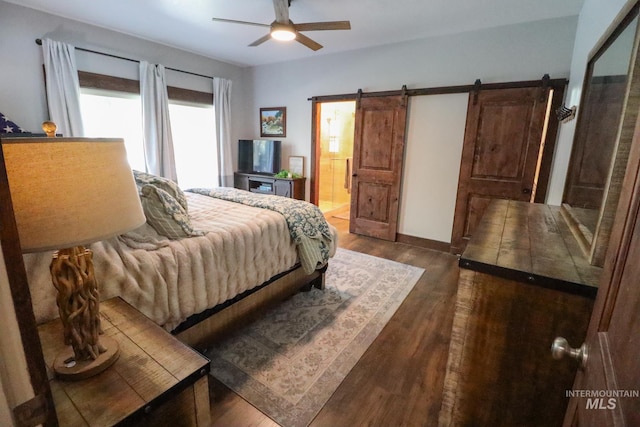 bedroom with connected bathroom, a ceiling fan, a barn door, and dark wood-style floors
