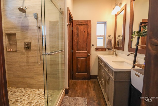 bathroom with a shower stall, a sink, and wood finished floors