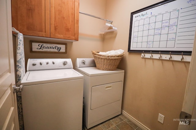 clothes washing area with cabinet space, dark tile patterned floors, baseboards, and washing machine and clothes dryer