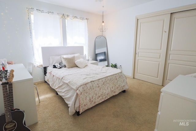 bedroom with baseboards, light colored carpet, and a closet