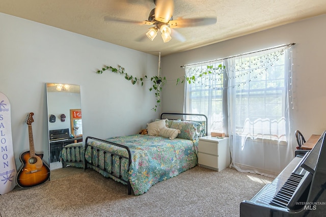 carpeted bedroom with ceiling fan and a textured ceiling