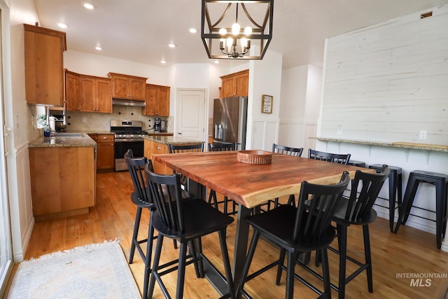dining area with recessed lighting, light wood-style flooring, and a notable chandelier