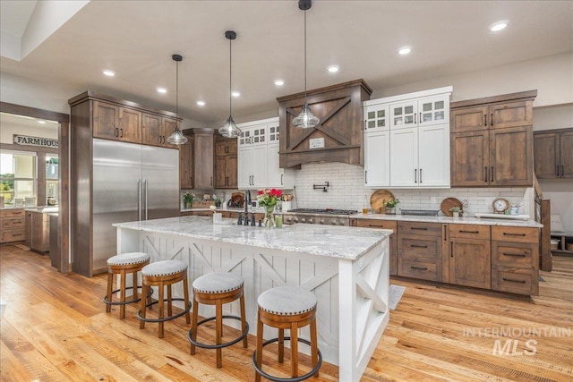 3800 Birch Ln, Emmett, ID 83617 - kitchen with light wood-style floors, tasteful backsplash, a kitchen island with sink, a breakfast bar, and light stone countertops