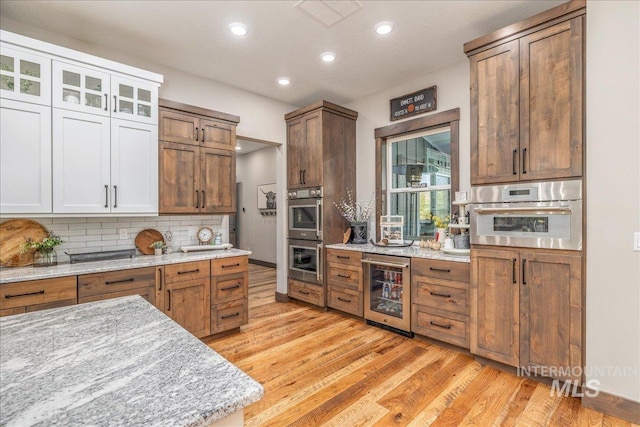 3800 Birch Ln, Emmett, ID 83617 - kitchen featuring beverage cooler, stainless steel double oven, recessed lighting, light wood-style flooring, and decorative backsplash