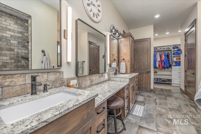 3800 Birch Ln, Emmett, ID 83617 - bathroom with double vanity, a spacious closet, stone finish flooring, recessed lighting, and a textured ceiling