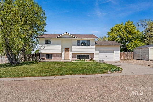 raised ranch with brick siding, fence, a garage, driveway, and a front lawn