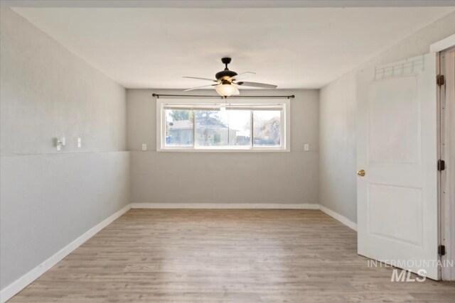 unfurnished room with a ceiling fan, baseboards, and light wood-style floors