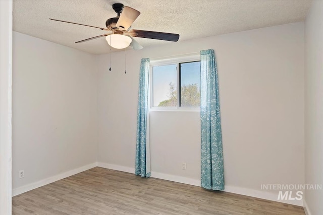 spare room featuring a textured ceiling, a ceiling fan, wood finished floors, and baseboards