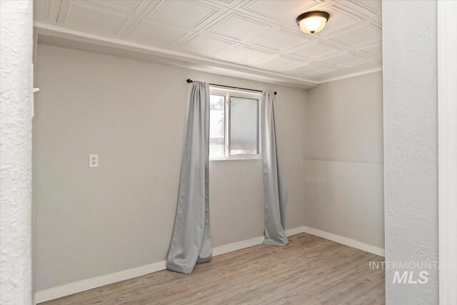 unfurnished room featuring baseboards, light wood-type flooring, and an ornate ceiling