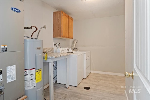 laundry room featuring independent washer and dryer, water heater, heating unit, light wood-type flooring, and cabinet space