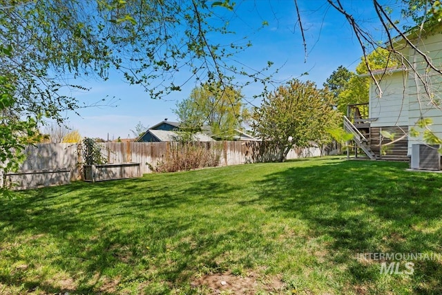 view of yard with central AC, fence private yard, and stairs