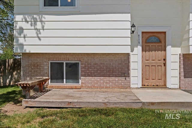 view of exterior entry featuring a deck and fence