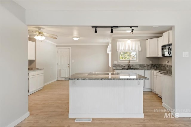 kitchen featuring stone countertops, black appliances, rail lighting, and light wood-style flooring