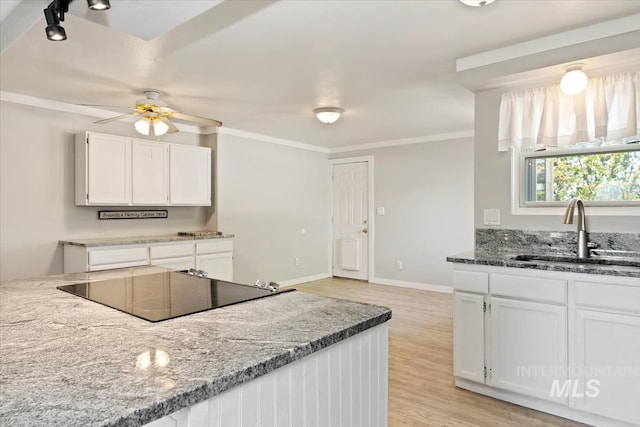 kitchen with white cabinets, ceiling fan, black electric cooktop, and a sink