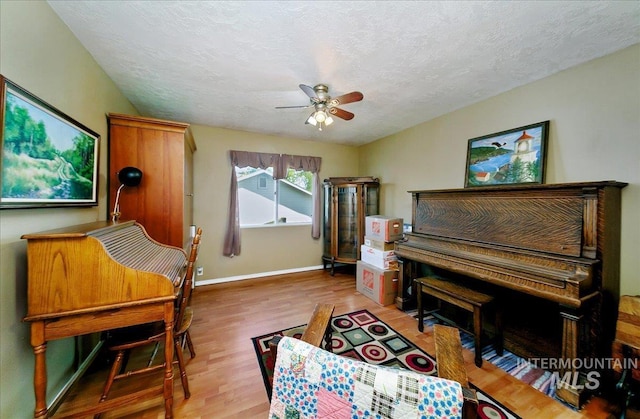 sitting room featuring a textured ceiling, baseboards, a ceiling fan, and wood finished floors