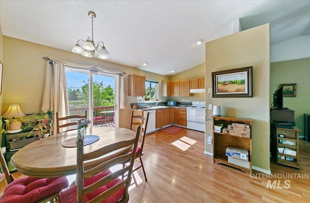 dining area with light wood-style floors, a notable chandelier, and lofted ceiling