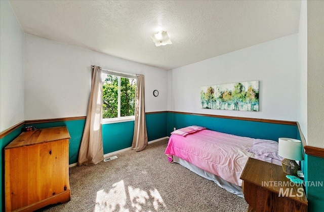 carpeted bedroom with visible vents and a textured ceiling