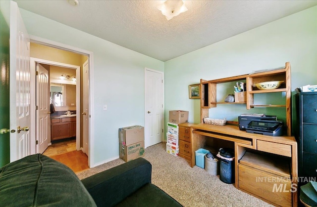 office area with a textured ceiling and light colored carpet