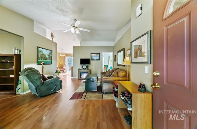 living room featuring ceiling fan, light wood-type flooring, and lofted ceiling