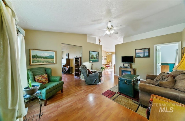 living area featuring a ceiling fan, a textured ceiling, light wood-type flooring, lofted ceiling, and a wealth of natural light