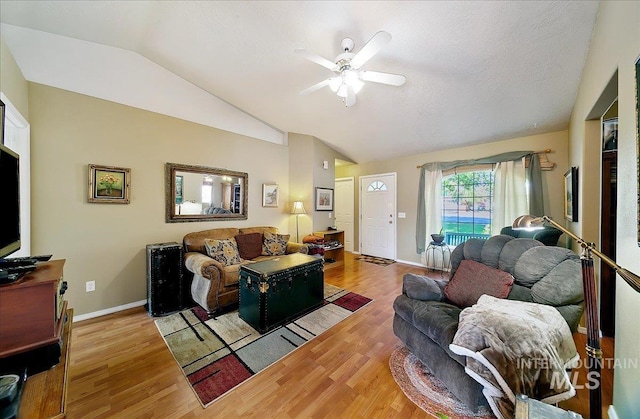 living room with a ceiling fan, baseboards, vaulted ceiling, and wood finished floors
