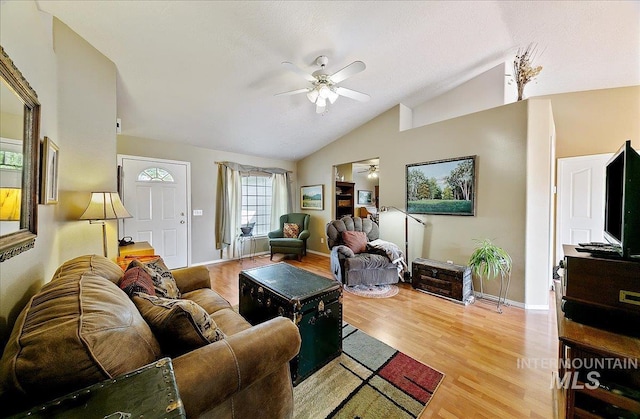 living room with baseboards, ceiling fan, vaulted ceiling, and light wood-type flooring