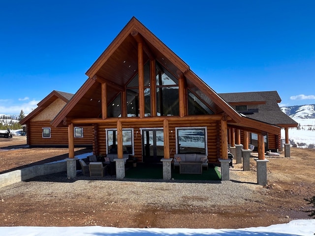 snow covered back of property featuring log exterior