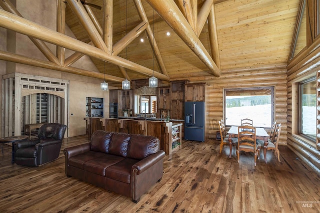 living room featuring rustic walls, dark wood finished floors, wooden ceiling, beam ceiling, and high vaulted ceiling