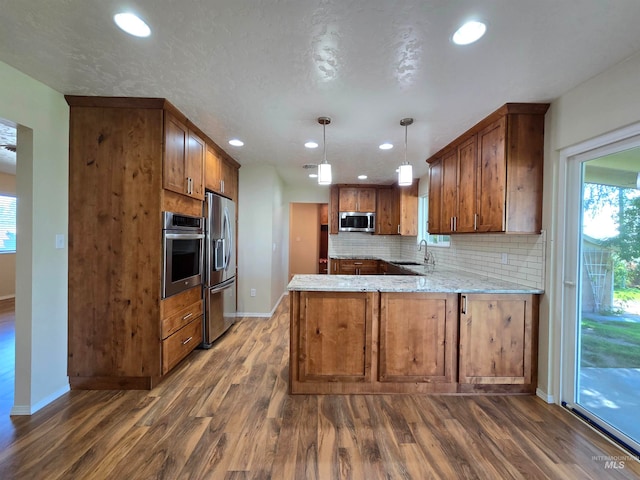 kitchen featuring appliances with stainless steel finishes, kitchen peninsula, and wood-type flooring