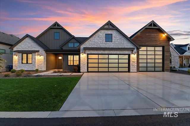 view of front facade featuring a front lawn, concrete driveway, board and batten siding, stone siding, and a garage