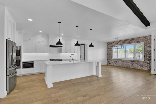 kitchen featuring appliances with stainless steel finishes, brick wall, light countertops, white cabinets, and light wood-style flooring
