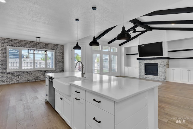 kitchen with open floor plan, a sink, light wood-type flooring, ceiling fan, and a textured ceiling