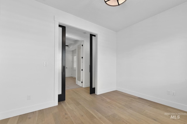 spare room featuring baseboards and light wood-type flooring