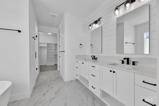 full bath featuring marble look tile flooring, baseboards, a spacious closet, and double vanity
