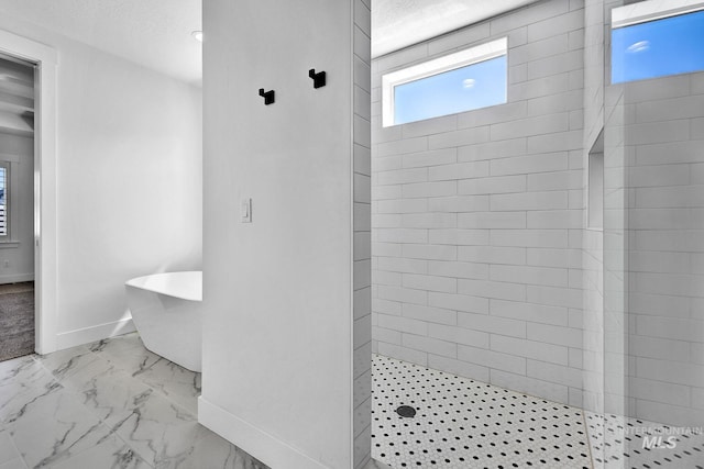 full bathroom with a walk in shower, marble finish floors, a freestanding bath, and baseboards