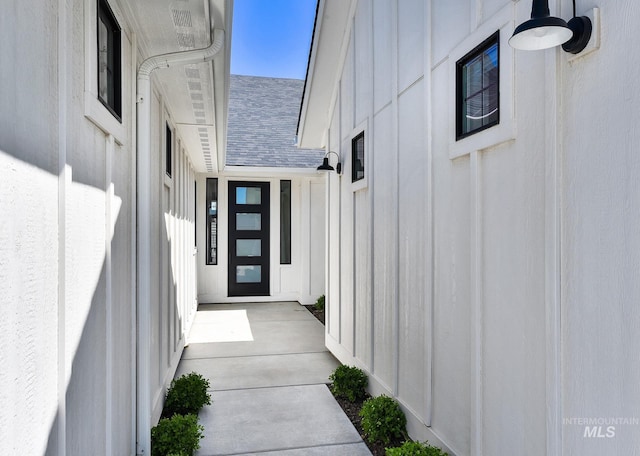 entrance to property with board and batten siding and a shingled roof