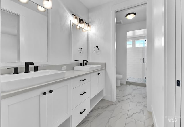 full bathroom featuring marble finish floors, toilet, a stall shower, double vanity, and baseboards