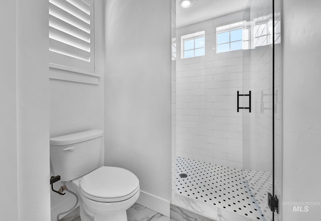 bathroom featuring marble finish floors, a shower stall, toilet, and baseboards