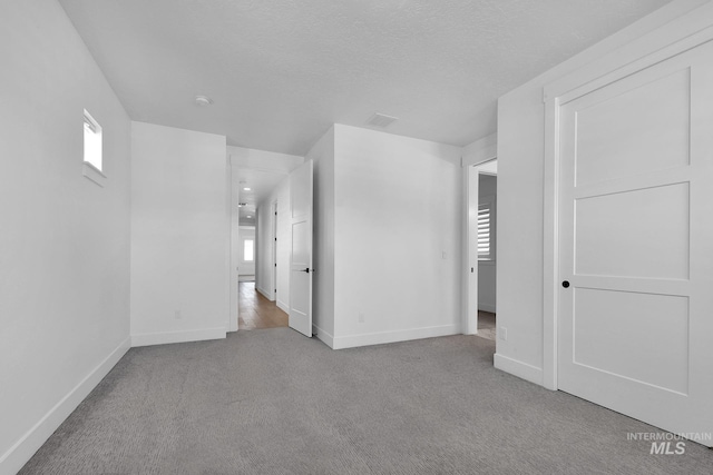 unfurnished bedroom featuring carpet floors, multiple windows, and baseboards