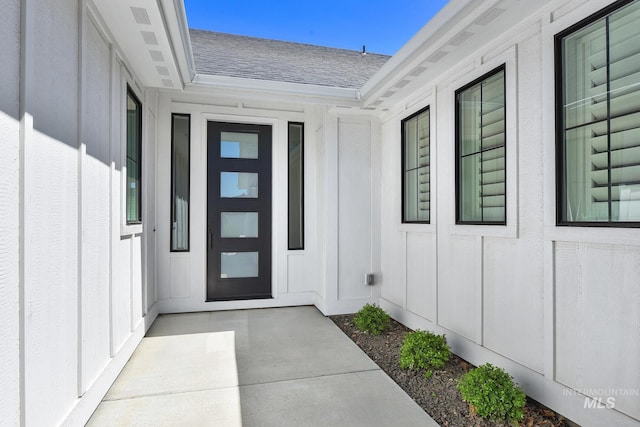 doorway to property featuring roof with shingles and board and batten siding