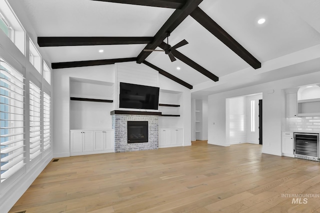 unfurnished living room with beverage cooler, a ceiling fan, a glass covered fireplace, light wood-style floors, and recessed lighting