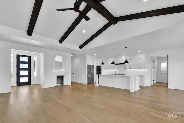 unfurnished living room with beverage cooler, recessed lighting, ceiling fan, light wood finished floors, and baseboards
