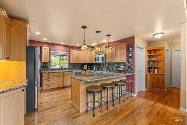 1611 Woodhaven Ln, Mccall, ID 83638 - kitchen featuring appliances with stainless steel finishes, a sink, light wood-style floors, a kitchen bar, and stone counters