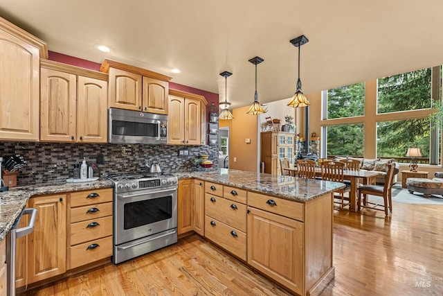 1611 Woodhaven Ln, Mccall, ID 83638 - kitchen with appliances with stainless steel finishes, a peninsula, light wood-style flooring, stone counters, and tasteful backsplash