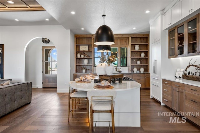 461 Centry Ave, Middleton, ID 83644 - kitchen featuring open shelves, a breakfast bar, arched walkways, white cabinets, and light countertops